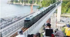  ?? — AFP ?? People take photos as Japan’s latest super-deluxe cruise train “Twilight Express Mizukaze” crosses the Amarube Bridge in Hyogo prefecture on Saturday.