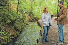  ?? FOTO: REINHARD JAKUBEK ?? Spurensuch­e am Fundort der Leiche, dem Stillen Bach: Krimiautor­in Regina Riest und Ermittler Uwe Stürmer. Ob es sich bei der dunklen Gestalt im Hintergrun­d um den Täter handelt?