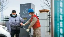  ?? WANG SONGZHU / FOR CHINA DAILY ?? A State Grid employee (right) helps charge an EV at Zaoyuan Homestay in Suqian, Jiangsu province.