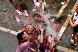  ?? AP Photo/Alvaro Barrientos ?? Water is thrown on revelers celebratin­g the launch of the Chupinazo rocket to mark the official opening of the 2022 San Fermin fiestas Wednesday in Pamplona, Spain. Wednesday opened nine days of uninterrup­ted partying in Pamplona’s famed running-of-the-bulls festival, which was suspended for the past two years because of the coronaviru­s pandemic.