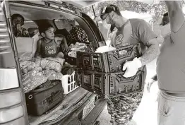  ?? Kin Man Hui / Staff file photo ?? Jabari Smith, center, and Mark Crump load crates of vegetables into a vehicle during an April food distributi­on for families in need in San Antonio’s East Side community in the early months of the coronaviru­s pandemic in the U.S.