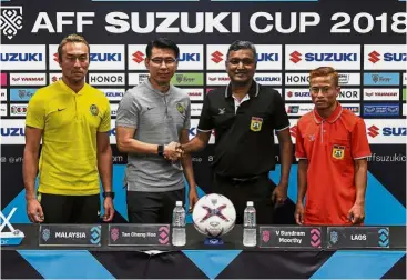  ?? — Bernama ?? One for the album: Malaysia and Laos coaches Tan Cheng Hoe and V. Sundrammoo­rthy shake hands as Malaysia and Laos players Khairul Fahmi Che Mat (left) and Soukaphone Vongchieng­kham look on ahead of their Suzuki Cup clash today.