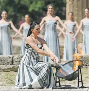  ?? ?? Una mujer prende la llama olímpica durante el ensayo de ayer en Grecia, previo a la ceremonia de hoy