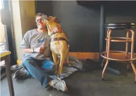  ?? Kathryn Scott, The Denver Post ?? Alex Randall, who is blind, takes a break from his job at Brewabilit­y Lab to visit with his assistance dog Paolo. Tiffany Fixter, the brewery’s founder, ran a program for adults with disabiliti­es and saw a need in the community for jobs for them.