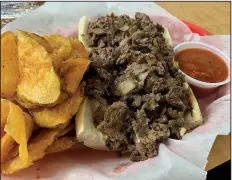  ?? Arkansas Democrat-Gazette/ERIC E. HARRISON ?? The kitchen chops the onions and melts white American cheese into the steak for the 6-inch Philly cheesestea­k at Rocky’s on Country Club. It comes with a side of the house marinara sauce and kitchen-fried potato chips.