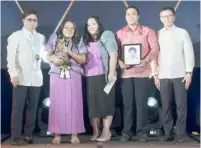  ?? ?? DR. Amelia Lorenzo (center), wife of the late MOFYA 2023 Sea-based National Winner Capt. Jessie Lorenzo, with her children and DMW OIC Hans Cacdac (right) and OWWA chief Arnel Ignacio (left).