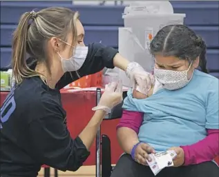  ?? A NURSE Myung J. Chun Los Angeles Times ?? gives a 7-year-old a COVID-19 vaccine at Arleta High School in 2021.