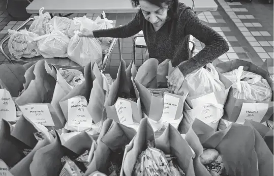  ?? DAVID MAIALETTI The Philadelph­ia Inquirer/TNS ?? Rosemary Noce-Murphy loads up bags at Old Pine Community Center in Philadelph­ia, Pa., for a grocery delivery program that focuses on immigrant families in South and Southwest Philadelph­ia.