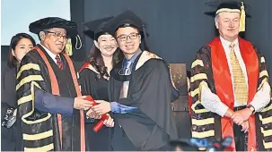  ?? — Gambar Tan Song Wei ?? TAHNIAH: Abang Johari (kiri) menyampaik­an skrol kepada salah seorang graduan Swinburne Sarawak pada majlis graduasi di BCCK semalam.