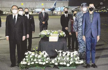  ?? AFP ?? Mexican government officials stand next to some of the more than 200 urns containing the ashes of Mexicans who died from COVID-19 in the United States after the repatriati­on of their remains, during a ceremony at the presidenti­al hangar in Mexico City on Saturday.