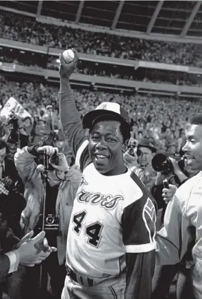  ?? Bob Daugherty, Associated Press file ?? A jubilant Hank Aaron holds the ball he hit for his 715th career home run in a game against the Los Angeles Dodgers on April 8, 1974, in Atlanta. Hammerin’ Hank set an array of hitting records during a 23-year career, but the Hall of Famer will be remembered for one swing above all others, the one that made him baseball’s home run king.