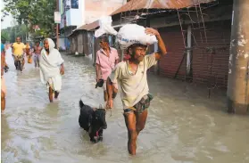  ?? Rehman Asad / AFP / Getty Images ?? Residents of the Gaibandha district of northern Bangladesh walk along a flooded street Thursday after heavy monsoon rain across the region.