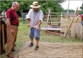 ?? FILE PHOTO ?? Luke Sensenig shows Stephen Moraux how to use a flail to beat the grain loose from the stalk at the Goschenhop­pen Folk Festival Aug. 11, 2017.