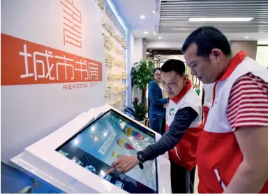  ??  ?? 居住在北京市朝阳区左­家庄的两位残疾人在城­市书房使用残疾人专用­的电子阅读器查找资料