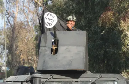  ??  ?? MOSUL: A soldier with elite counterter­rorism forces rides atop of an armored vehicle celebratin­g as he holds a flag of the Islamic State group as Iraqi special forces fight against Islamic State militants to regain control of Mosul University, in the...