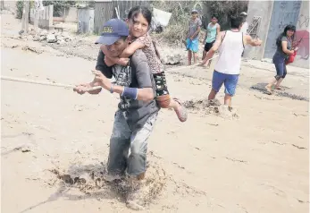  ??  ?? Peruanos cruzan una calle inundada sujetándos­e de una cuerda, tras el desbordami­ento del río Rimac, en la zona de Carapongo, en Huachipa, en la provincia de Lima, desde hace semanas por intensas lluvias.