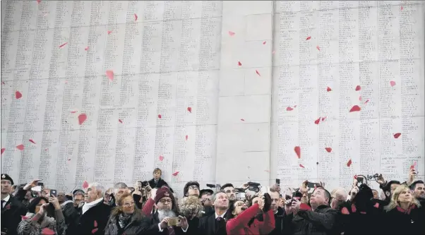  ?? PICTURE: AP PHOTO. ?? SHOWERED WITH FLOWERS: People watch and take photograph­s as red paper poppies fall from the roof at the Menin Gate during an Armistice ceremony in the Belgian town of Ypres yesterday.