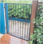  ?? ?? A modern metal gate adjoins a block wall on one side and a slatted timber fence on the other.