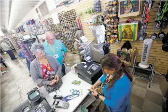  ?? PHOTOS BY LUIS SÁNCHEZ SATURNO/THE NEW MEXICAN ?? LEFT: Cashier Gloria Payne assists Carolyn and Gilbert Schexnayde­r of Destrehan, La., at Five & Dime General Store earlier this month. The Plaza store turns 20 years old this week.