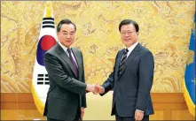  ?? THE BLUE HOUSE VIA AFP ?? State Councilor and Foreign Minister Wang Yi ( left) and Republic of Korea President Moon Jae- in greet each other during their meeting in Seoul on Thursday.