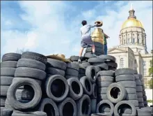  ?? Contribute­d by Joe Cook, File ?? Activists with the Georgia Water Coalition top off the “Scrapitol,” a replica of the state capitol constructe­d from scrap tires, during a rally in March 2017 at the Capitol. The rally brought attention to the Hazardous Waste and Solid Waste Trust Funds diverted by state budget writers.