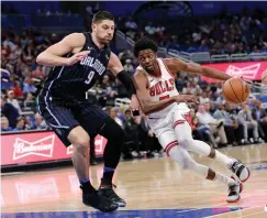  ?? Associated Press ?? ■ Chicago Bulls' Justin Holiday, right, drives around Orlando Magic's Nikola Vucevic (9) during the first half of an NBA basketball game Friday in Orlando, Fla.