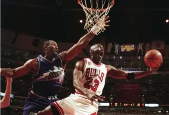  ?? AP FIle ?? LIKE MIKE: The Chicago Bulls' Michael Jordan (23) goes up and under Utah Jazz forward Karl Malone, left, as he drives to the hoop during the third quarter of Game 2 in the NBA Finals June 4, 1997, in Chicago.