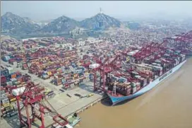  ?? BLOOMBERG ?? A container ship is docked as shipping containers stand in a terminal at the Yangshan Deep Water Port in Shanghai, China, on Friday.