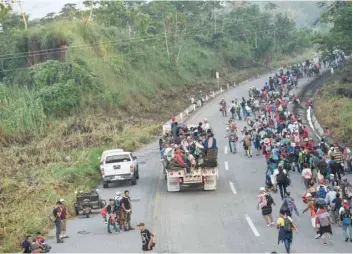 ?? — AFP ?? Honduran migrants taking part in a caravan heading to the US, walk alongside the road in Huixtla, Chiapas state, Mexico, on Wednesday.