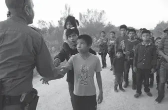  ?? Photos by Jerry Lara / Staff photograph­er ?? Migrants reach out to shake hands with Border Patrol Agent Carlos Ruiz as they surrender Thursday after crossing the Rio Grande near the Anzalduas Internatio­nal Bridge in Hidalgo County.