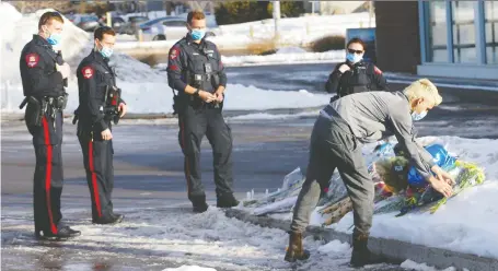  ?? DARREN MAKOWICHUK ?? District 5 officers pay tribute as citizens continue to lay flowers at the Falconridg­e location where their colleague, Sgt. Andrew Harnett, was killed Thursday night. Following a New Year's Day manhunt, two teenagers were arrested and charged with first-degree murder.