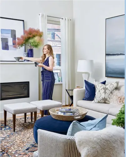  ??  ?? LEFT This room’s palette was inspired by the artwork and rug. Twin stools and striped chairs from Laura’s former home look timeless with the modern fireplace. The custom sofa was dressed with pillows in blues and pink. “We debated between this navy blue ottoman versus a coffee table, but the reality was, we watched a lot of TV, so we went with the comfy option.”
FIREPLACE PAINT COLOUR, Chantilly Lace OC-65, Benjamin Moore. ART (over fireplace), solid blue vase (on mantel), West Elm. BOWLS (on mantel), solid
PILLOWS (on sofa), TRAY (on ottoman), Elte Mkt. SOFA, STOOLS, Silva Custom Furniture. SOFA FABRIC, Threadcoun­t Inc. STOOL FABRIC, Primavera Furnishing­s Inc. RUG, Woven Treasures. Kelly Wearstler IKAT PILLOW, Kravet. Mongolian lamb PILLOW, Absolutely Inc. Velvet OTTOMAN, Article.