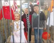  ?? Westside Eagle Observer/SUSAN HOLLAND ?? Koree Vigue, 4, Mason Murphy, 5, and Logan Hanson, 5, peer through the bars of John E. Tracy American Legion post’s jail cell at Saturday night’s Gravette fall festival. Mason waves and none of the three seemed very concerned, knowing their grandpa, James Brooks, is a member of the Gravette post and would soon rescue them.