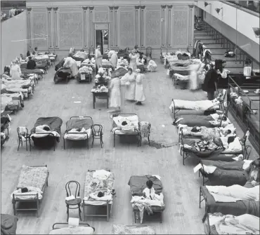  ?? LIBRARY OF CONGRESS VIA AP, FILE ?? In this 1918photo made available by the United States Library of Congress, volunteer nurses from the American Red Cross tend to influenza patients in the Oakland Municipal Auditorium, used as a temporary hospital.