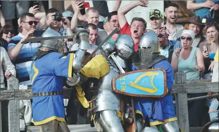  ?? SERGEI SUPINSKY / AGENCE FRANCE-PRESSE ?? Spectators react as knights in heavy armor battle during the four-day world championsh­ip at the annual medieval combat festival held in a medieval fortress near Kiev, Ukraine, on Saturday.