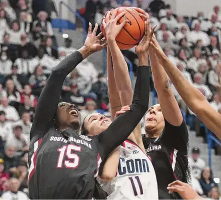  ?? Tyler Sizemore/Hearst Connecticu­t Media ?? UConn guard Lou Lopez Senechal, center, goes up for a rebound between South Carolina forwards Laeticia Amihere, left, and Kamilla Cardoso on Sunday.