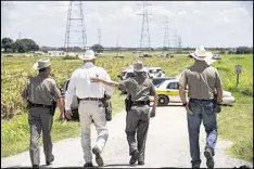  ?? RALPH BARRERA / AUSTIN AMERICAN- ?? Texas DPS Trooper Robbie Barrera (center right) puts her arm around Caldwell County Sheriff Daniel Law as he arrives on the scene of a hot-air balloon crash Saturday near Lockhart, Texas.