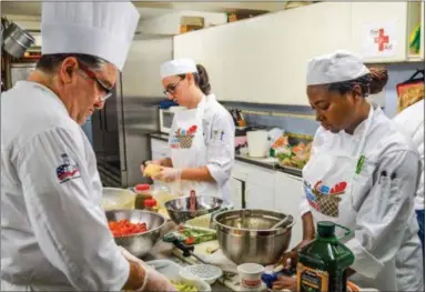  ?? SUBMITTED PHOTO ?? Chef Ben Vozzo, left, head chef at Culinary Arts Institute at Montgomery County Community College, helps prepare a meal with school members at Haws Kitchen in Norristown to launch Valley Forge Tourism’s annual food drive.