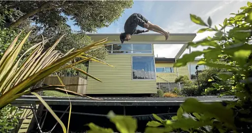  ?? ROBERT KITCHIN/STUFF ?? Jack Keenan, 13, plays on the trampoline outside his family’s architectu­rally-designed former state house in Wellington. It is now on the market.