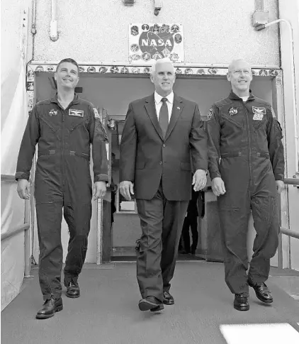  ?? RED HUBER/ORLANDO SENTINEL ?? Vice President Mike Pence, center, is flanked by NASA astronaut Reid Wiseman, left, and Patrick Forrester, NASA Chief astronaut, as they walk out of crew headquarte­rs in 2017 at the Kennedy Space Center. Pence will visit the Space Coast on Tuesday for a SpaceX launch.
