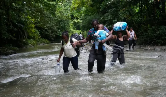  ?? FOTO: FERNANDO VERGARA/TT-AP ?? ■
Forsande floder är bara en av farorna i Darién-gapet. Här vadar en grupp haitier i ett av områdets vattendrag. Bild från oktober förra året.