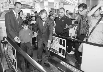  ??  ?? Mohtar demonstrat­es on how to use the escalator to a pupil. — Bernama photo