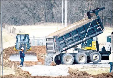  ?? (NWA Democrat-Gazette/Mike Eckels) ?? A bulldozer operator watches as a truck dumps a load of gravel over the freshly cut path that will become the west end of Veterans Park walking trail in Decatur. Work resumed on the project after extreme winter weather forced a delay in the constructi­on schedule.