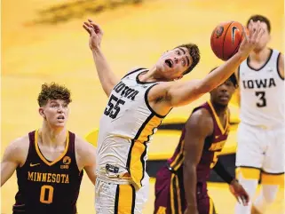  ?? CHARLIE NEIBERGALL/ASSOCIATED PRESS ?? Iowa’s Luka Garza catches a pass over Minnesota center Liam Robbins (0) during the second half Sunday. Garza, one of the country’s best players, scored 33 points in the Hawkeyes’ victory.