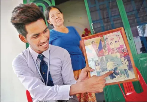  ?? HONG MENEA ?? Adopted son Heng Neurn points at a family photograph that was taken during a trip to Kampot together with his mother and father when he was a child.