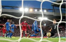  ??  ?? Mohamed Salah scores the first Liverpool goal, slipping the ball past Leicester City keeper Kasper Schmeichel.