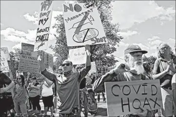  ?? NANCY LANE/BOSTON HERALD ?? Sal Lando, center, holds signs during a protest against mandatory flu shots Aug. 30 at the Massachuse­tts State House.