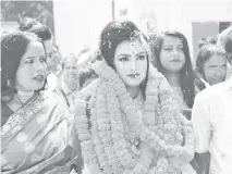  ?? — AFP photo ?? Relatives of groom Islam welcome bride Khushi (centre) with a floral wreath as she arrives to groom’s house during their wedding in Meherpur.