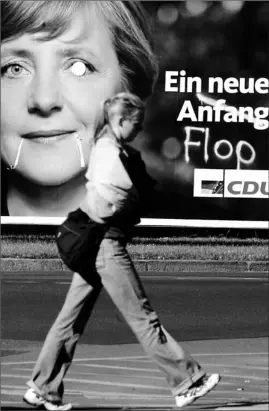  ?? MICHAEL URBAN / AGENCE- FRANCE PRESSE ?? A woman walks past a election billboard in Berlin for Angela Merkel reading “ A New Beginning,” with the word “Beginning” crossed out and replaced by the word “Flop.”