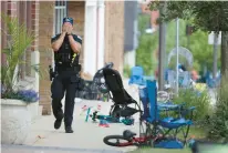  ?? BRIAN CASSELLA/CHICAGO TRIBUNE VIA AP ?? A Lake County police officer walks down Central Ave in Highland Park, Illinois, on Monday after a shooter fired on the northern suburb’s Fourth of July parade.